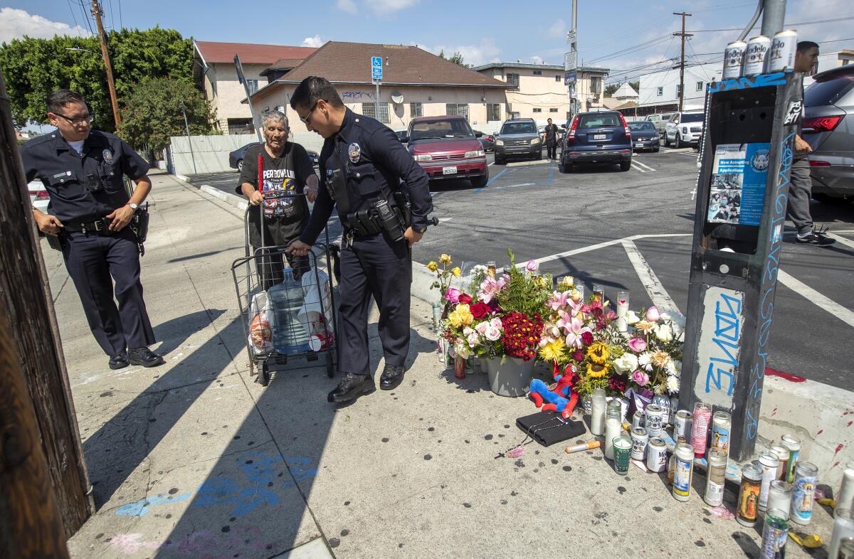 LAPD officers Nicholas Torres, left, and Erick Rodriguez help a blind man