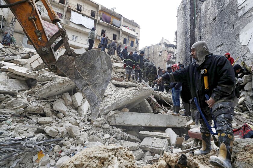 Officials search through the wreckage of collapsed buildings, in Aleppo, Syria, Monday, Feb. 6, 2023. 