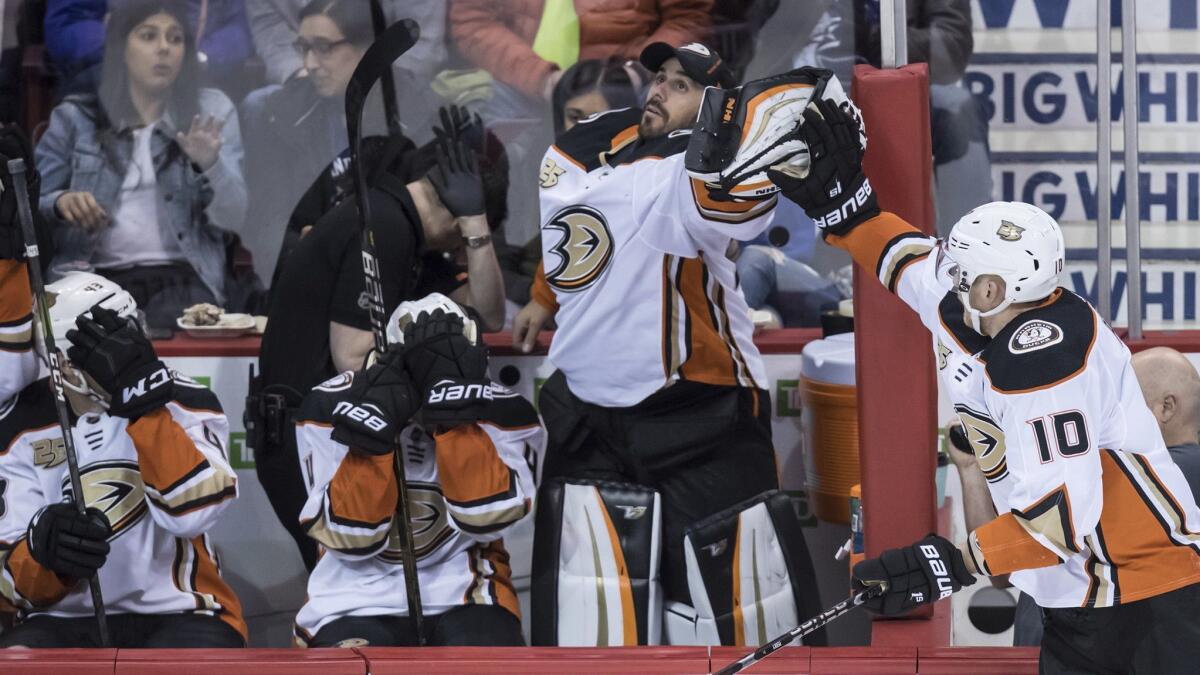 Ducks goalie Ryan Miller, second right, catches a puck that went out of play as Corey Perry (10) reaches for it and Ducks' Jaycob Megna, left, and Cam Fowler, second left, cover their faces during the second period in Vancouver on March 26, 2019.