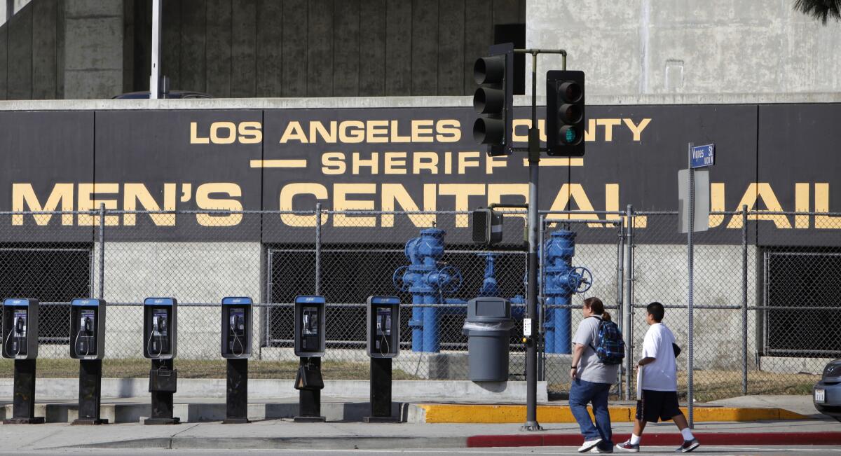 Two people walking outside a building with a sign that says Los Angeles County Sheriff Men's Central