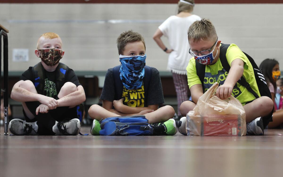 Tres estudiantes de primaria portando mascarillas para evitar la propagación de COVID19.