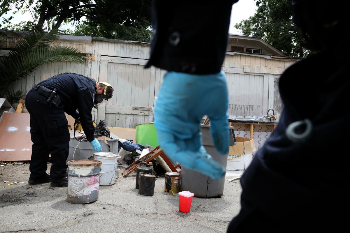 Hazardous material specialists check items in a Los Angeles alley recently cleared of 16 tons of illegally dumped trash that served as a backdrop Thursday for Mayor Eric Garcetti to launch a new initiative to clean up Los Angeles' streets, sidewalks and alleys.