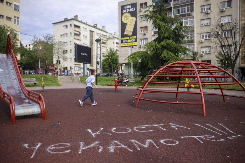 A boy walks past graffiti on a playground that reads: "Kosta we are waiting for you" in Belgrade, Serbia, Saturday, May 6, 2023. Kosta Kecmanovic is a 13-year-old boy who on Wednesday used his father's guns to kill eight fellow students and a guard. (AP Photo/Armin Durgut)