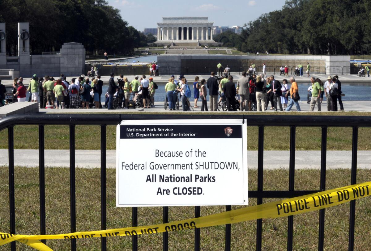 In this Oct. 2 photo people visit the closed World War II Memorial on the National Mall in Washington, despite signs stating that the national parks are closed due to the federal shutdown.