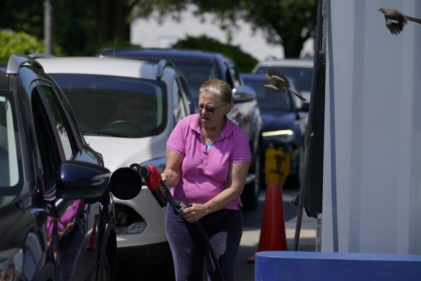 A customer pumps gas at Costco, as others wait in line, on Tuesday, May 11, 2021, in Charlotte, N.C. Gasoline futures are ticking higher following a cyberextortion attempt on the Colonial Pipeline, a vital U.S. pipeline that carries fuel from the Gulf Coast to the Northeast. (AP Photo/Chris Carlson)