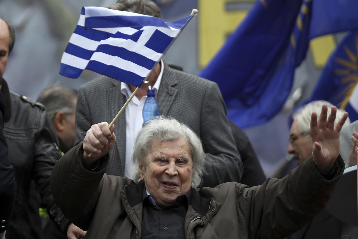 FILE - In this Sunday, Feb. 4, 2018 file photo, famous Greek composer Mikis Theodorakis waves a Greek flag after his speech at a rally in Athens, Greece. Mikis Theodorakis, the beloved Greek composer whose rousing music and life of political defiance won acclaim abroad and inspired millions at home, died on Thursday, Sept. 2, 2021. He was 96. (AP Photo/Petros Giannakouris, File)
