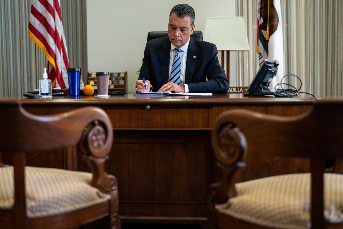 Senator Alex Padilla speaks on a cellphone while standing next to Senator Dianne Feinstein in a Capitol chamber