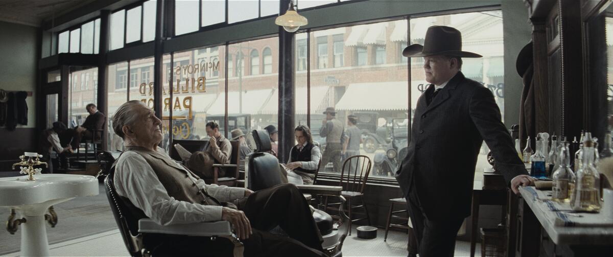 Two men talk in a barbershop.