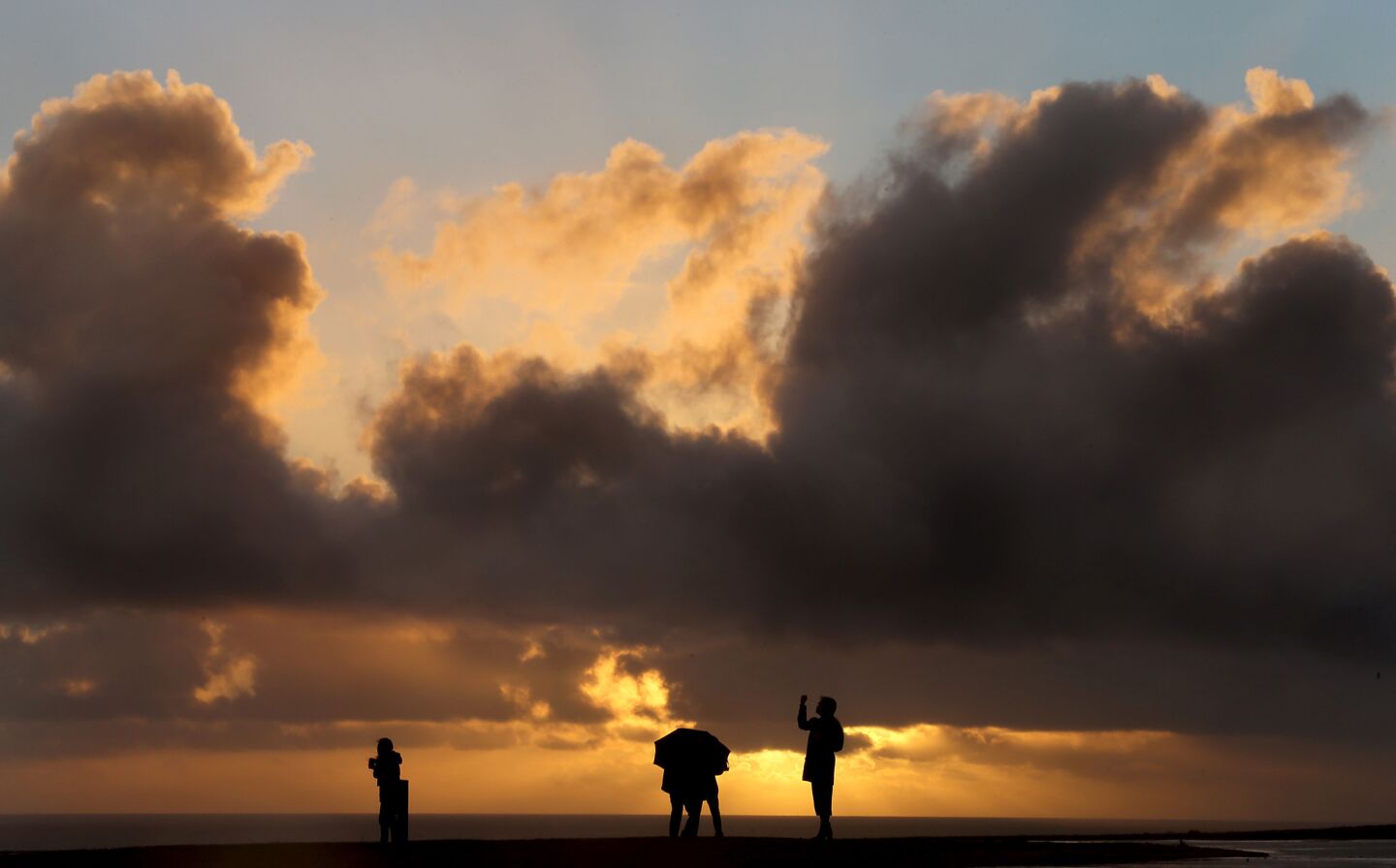 Visitors to Angels Gate Park in San Pedro are framed between the sea and sun-tinged clouds as the first storm of El Nino blows ashore.