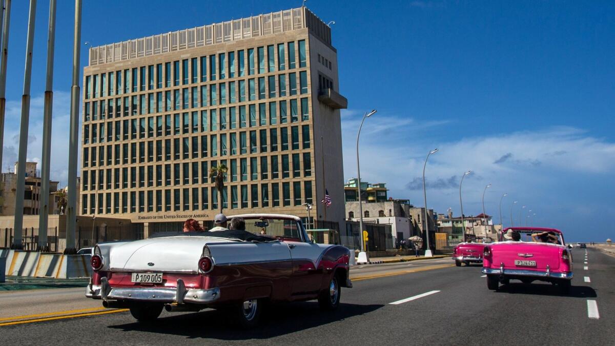 Tourists ride classic convertible cars on the Malecon past the U.S. Embassy in Havana.