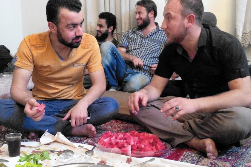 Abdulkareem Laila, left, better known as Abu Firas, a spokesman for the Syrian rebel group Islamic Front, shares a meal with rebel fighter Omar Hamoude in Aleppo.