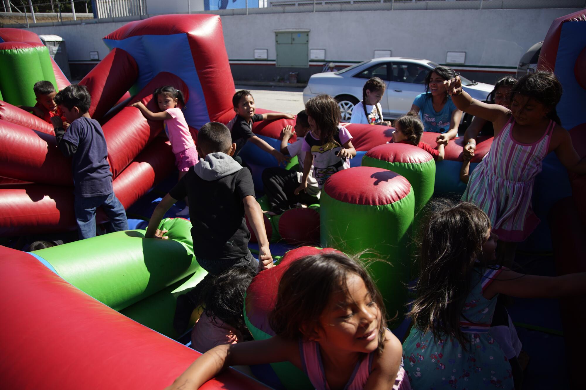 Asylum-seeking children take turns playing on a large inflatable bouncer 