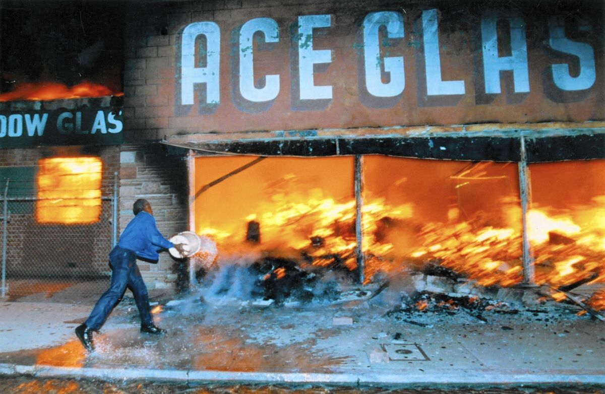 A shop owner hurls a bucket of water on a fire.