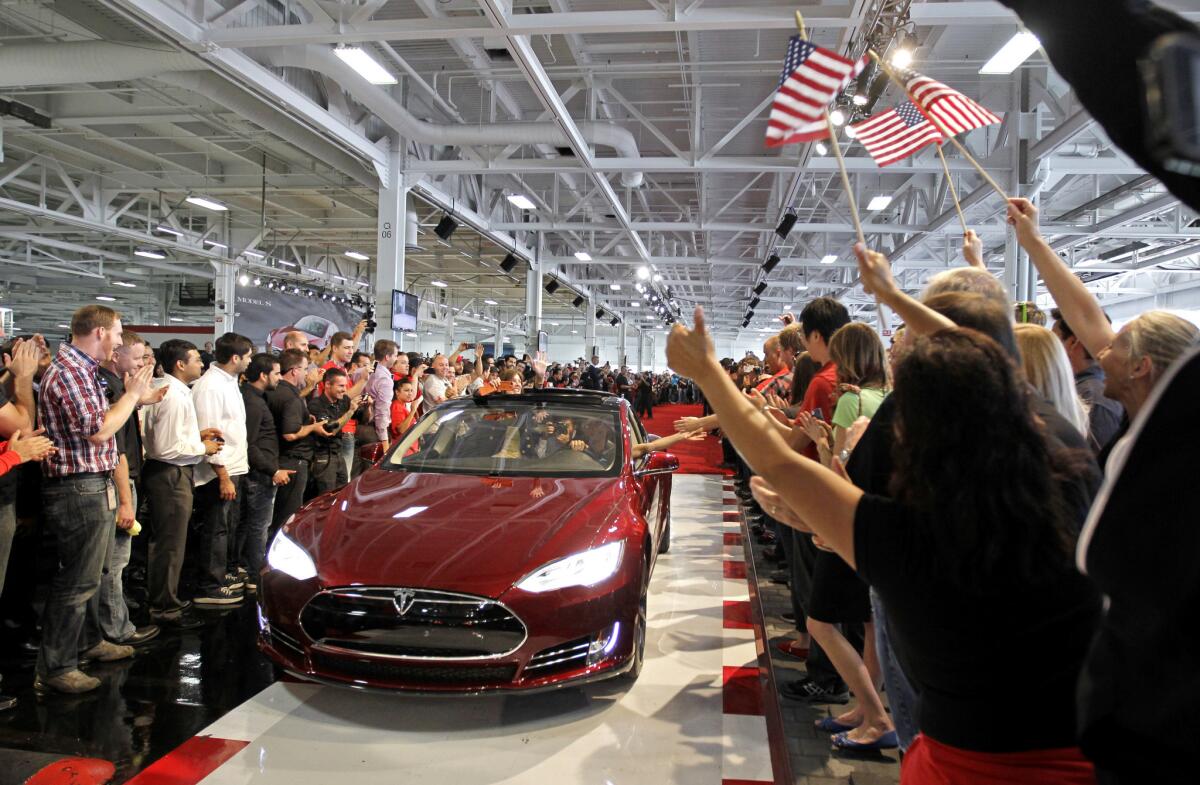 Tesla workers cheer on one the first Tesla Model S cars sold during a rally at the Tesla factory in Fremont, Calif, on June 22, 2012.