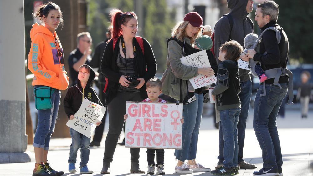 Phinehas Hogue, de 4 años, de Burbank sostiene un cartelón que dice: ‘las niñas son fuertes’ junto a su familia y amigos durante la segunda marcha anual de mujeres en Los Ángeles.