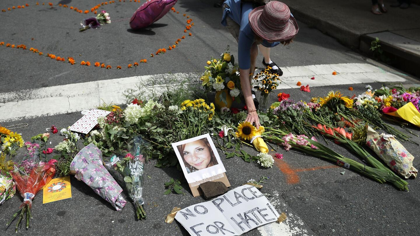 A woman places flowers at a memorial to 32-year-old Heather Heyer, who was killed when a car plowed into a crowd of people protesting the white nationalist Unite the Right rally in Charlottesville, Va.