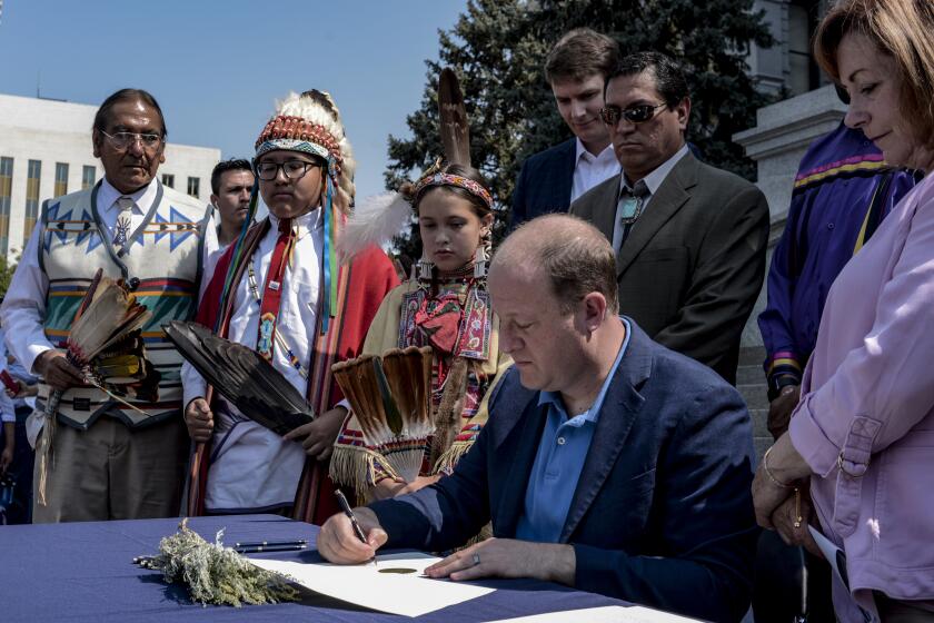 Colorado Gov. Jared Polis signs an executive order that rescinds proclamations from Colorado Territorial Gov. John Evans in 1864, at the Capitol in Denver, Colo. on Tuesday, Aug. 17, 2021. Gov. Polis handed sage to the various tribe representatives and speakers after signing. (Rebecca Slezak/The Denver Post via AP)
