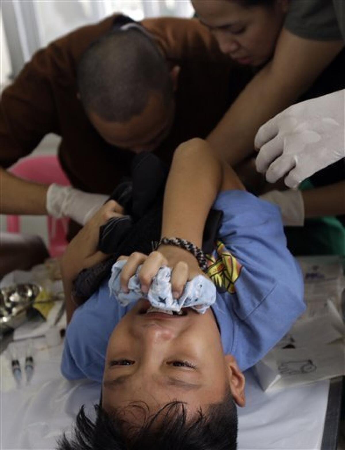A boy tries to control himself as doctors work on him during a free circumcision surgery Saturday, May 7, 2011, in Marikina city, east of Manila, Philippines. Officials say hundreds of boys in a Philippine city have turned out for a day-long "circumcision party" that aims to break the world record for the most number of participants in a circumcision event. (AP Photo/Pat Roque)