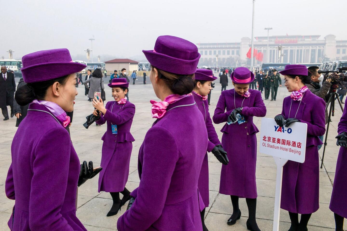 Hostesses take pictures at the opening session of the Chinese People's Political Consultative Conference at the Great Hall of the People in Beijing.