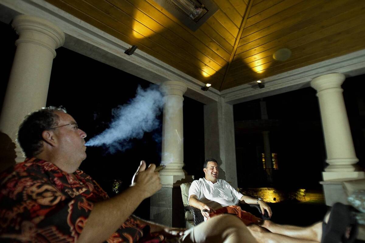Ed Richmond, left, and Eddie Antonini hang out, smoke cigars and have drinks in Richmond's outdoor "cigar cave."