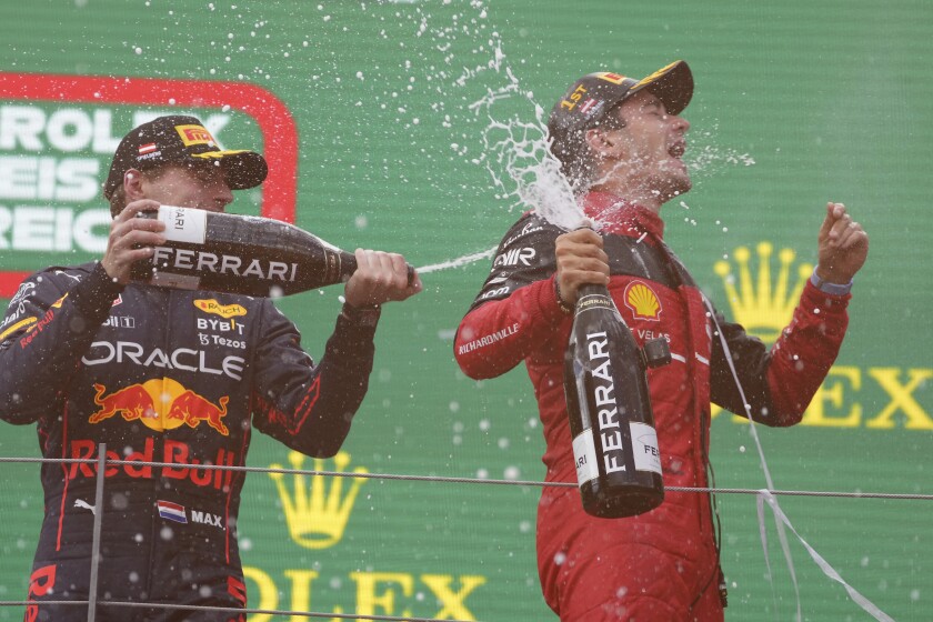 Ferrari driver Charles Leclerc, right, of Monaco, celebrates on the podium with second placed Red Bull driver Max Verstappen, of the Netherlands, after winning the Austrian F1 Grand Prix at the Red Bull Ring racetrack in Spielberg, Austria, Sunday, July 10, 2022. (AP Photo/Matthias Schrader)
