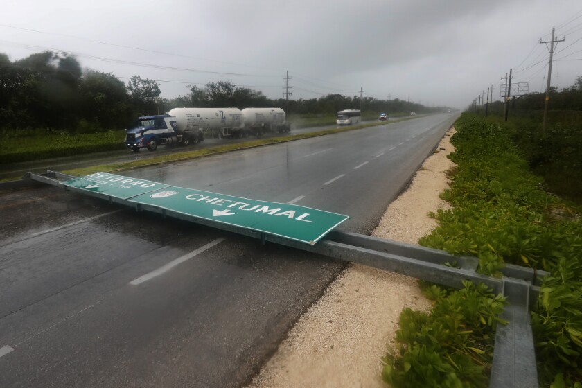 A fallen green road sign lies across three lanes of a highway 
