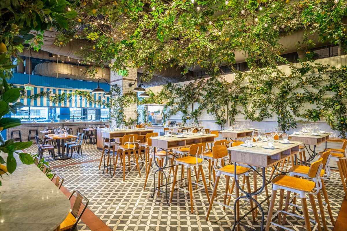 A photo of a dining room at the Capri pop-up at Eataly: hanging plants, tiled floors and high-topped seating.