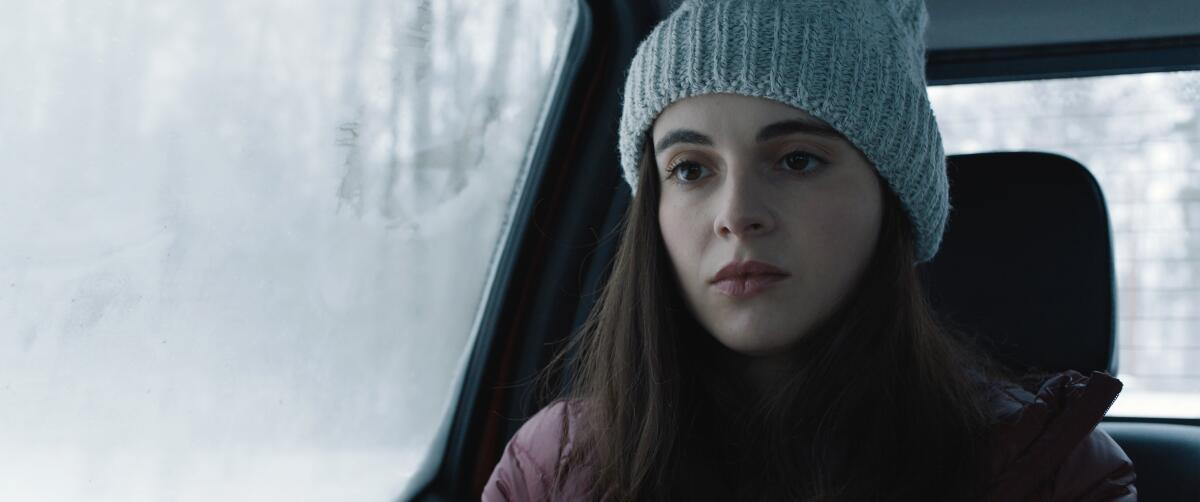A young woman sits in a car with a snowy backdrop in the movie “How to Deter a Robber.”