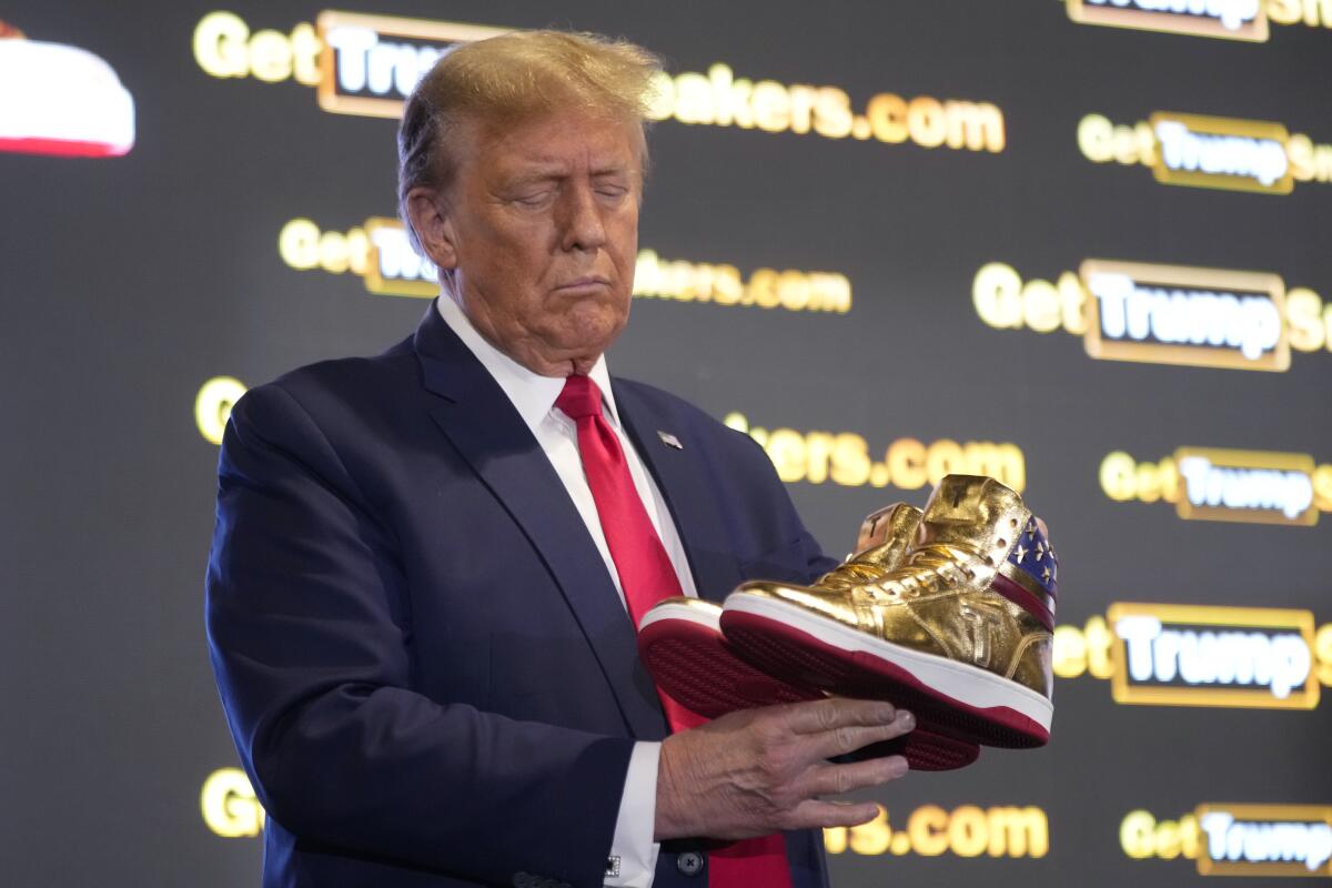 Republican presidential candidate Donald Trump holds gold Trump sneakers at Sneaker Con Philadelphia on Saturday.