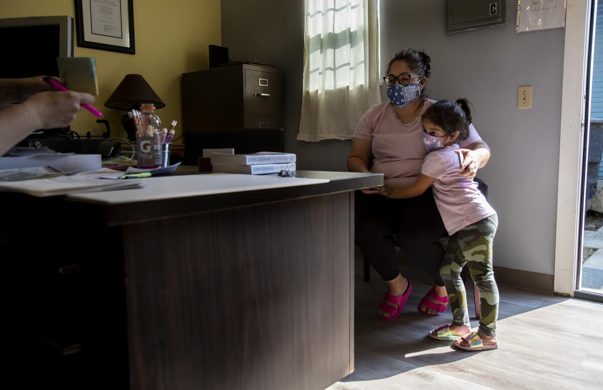 A woman and child wait by a desk in an office.