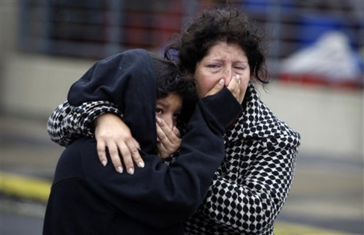 Women cover their faces from tear gas, shot by police officers, during looting in Concepcion, Chile, Sunday, Feb. 28, 2010. A 8.8-magnitude earthquake hit Chile early Saturday. (AP Photo/ Natacha Pisarenko)