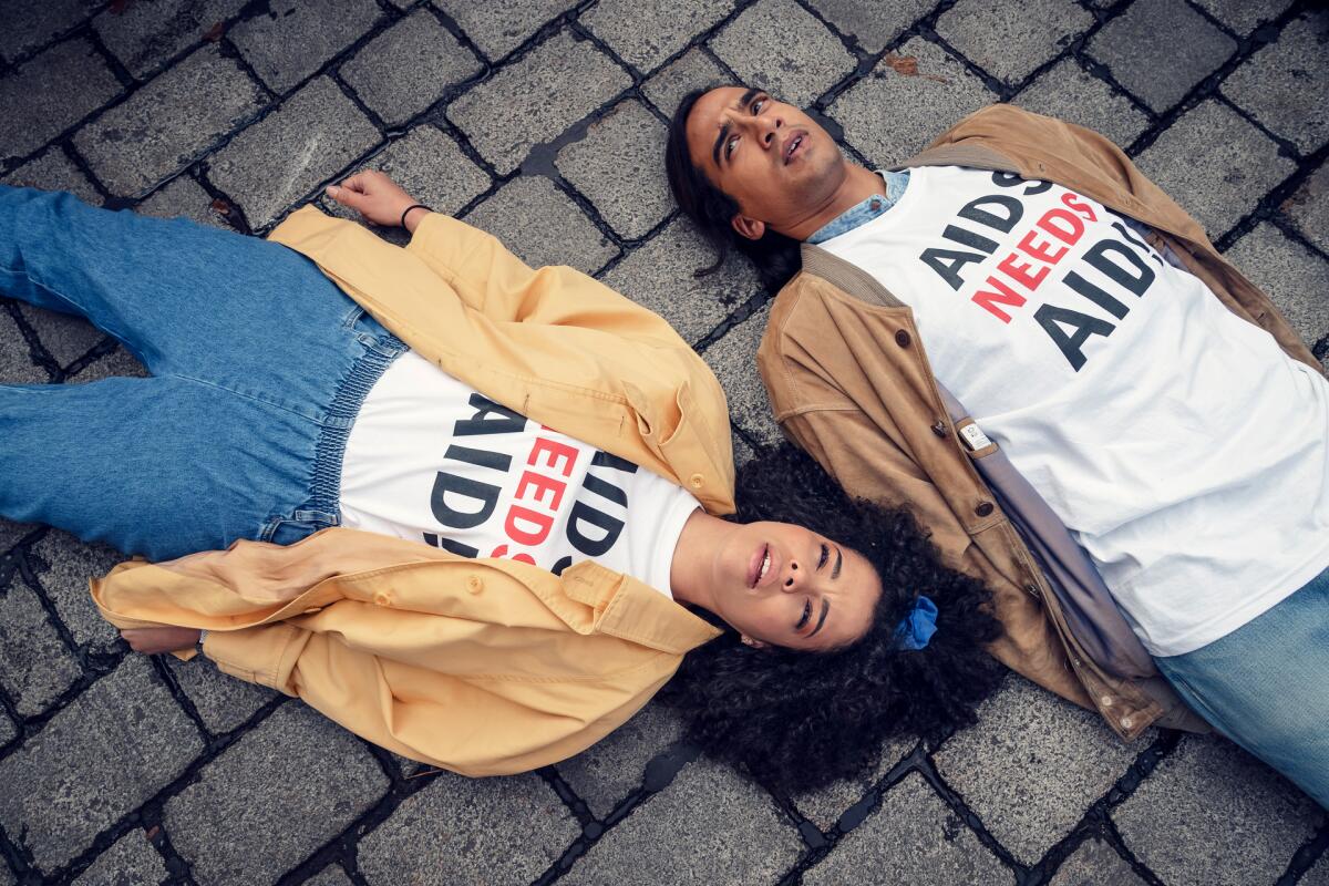 Two AIDS activists lying on a cobblestone street during a die-in in the miniseries "It's a Sin."