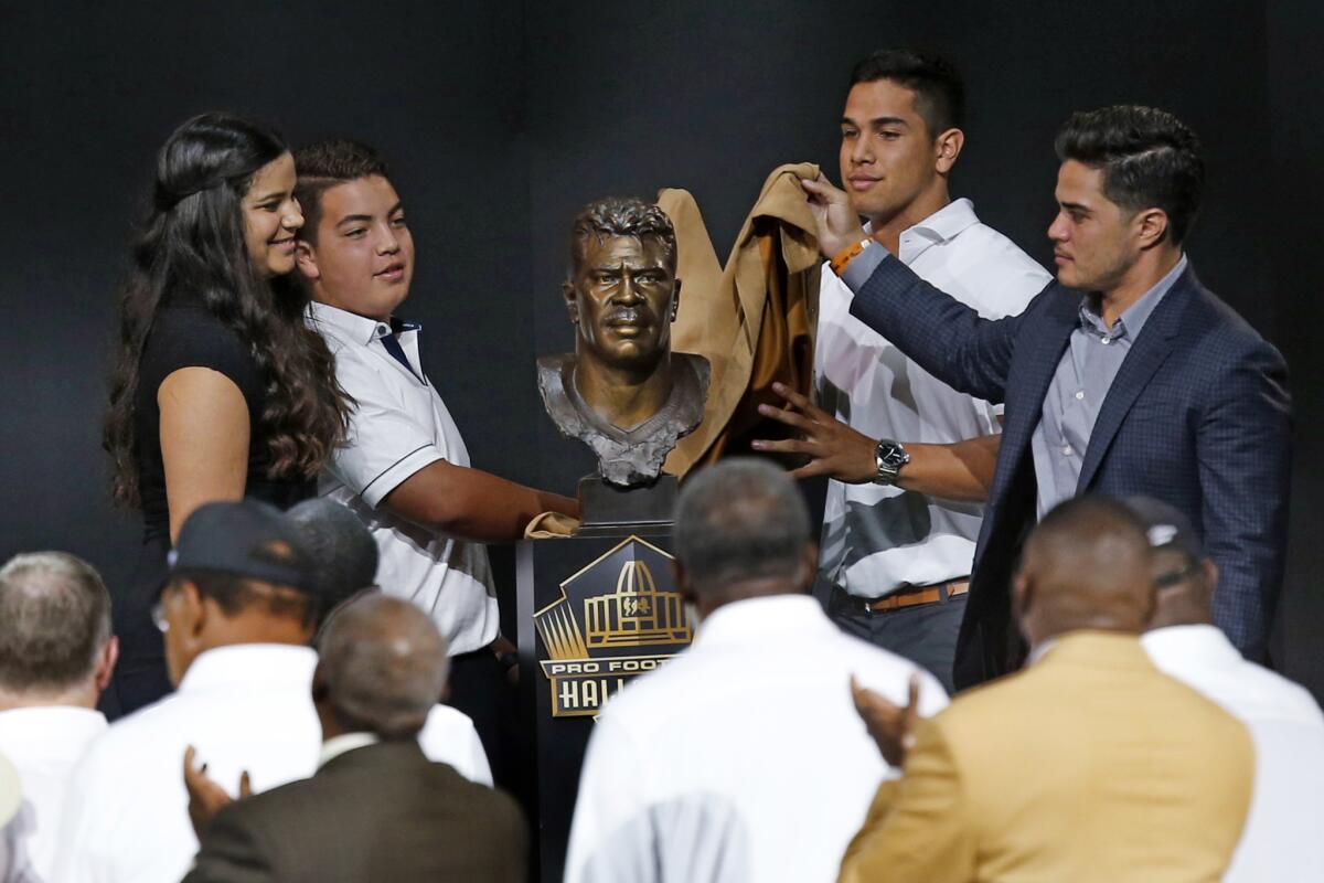 Children of former NFL player Junior Seau -- Sydney, left, Hunter, Jake, and Tyler -- unveil the bust of their late father during the Pro Football Hall of Fame induction ceremony Saturday in Canton, Ohio.