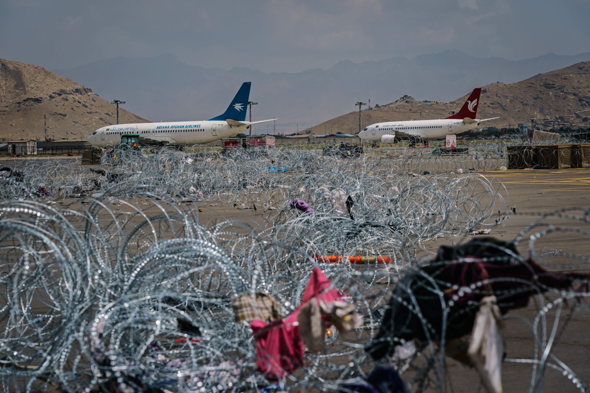 Barbed wire covers the ground with jetliners in the background