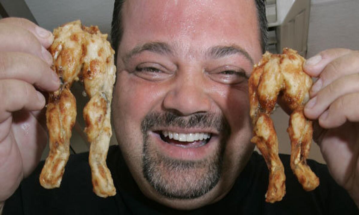 Chicken Charlie (a.k.a. Charles Boghosian) holds deep-fried frog legs. He sells about 2,000 legs in a typical, three-week county fair.