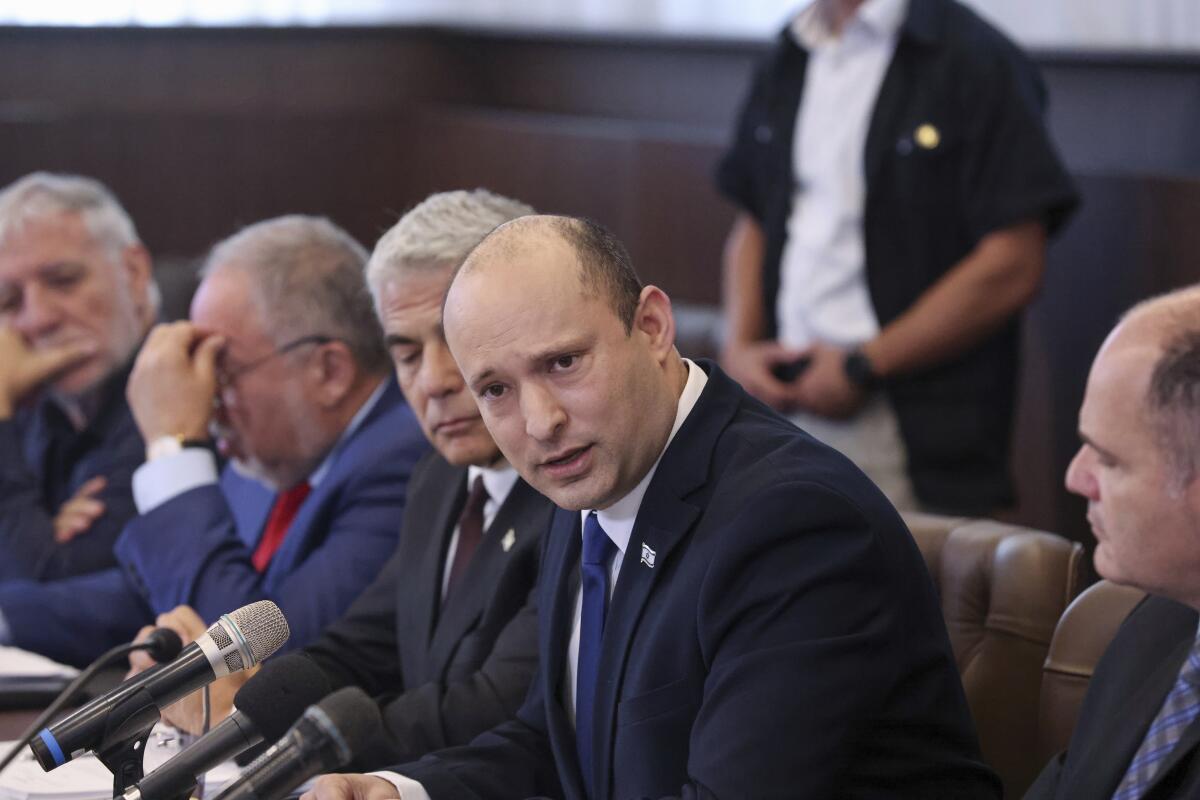 Naftali Bennett, among a row of seated men in suits and ties, speaks into a microphone.