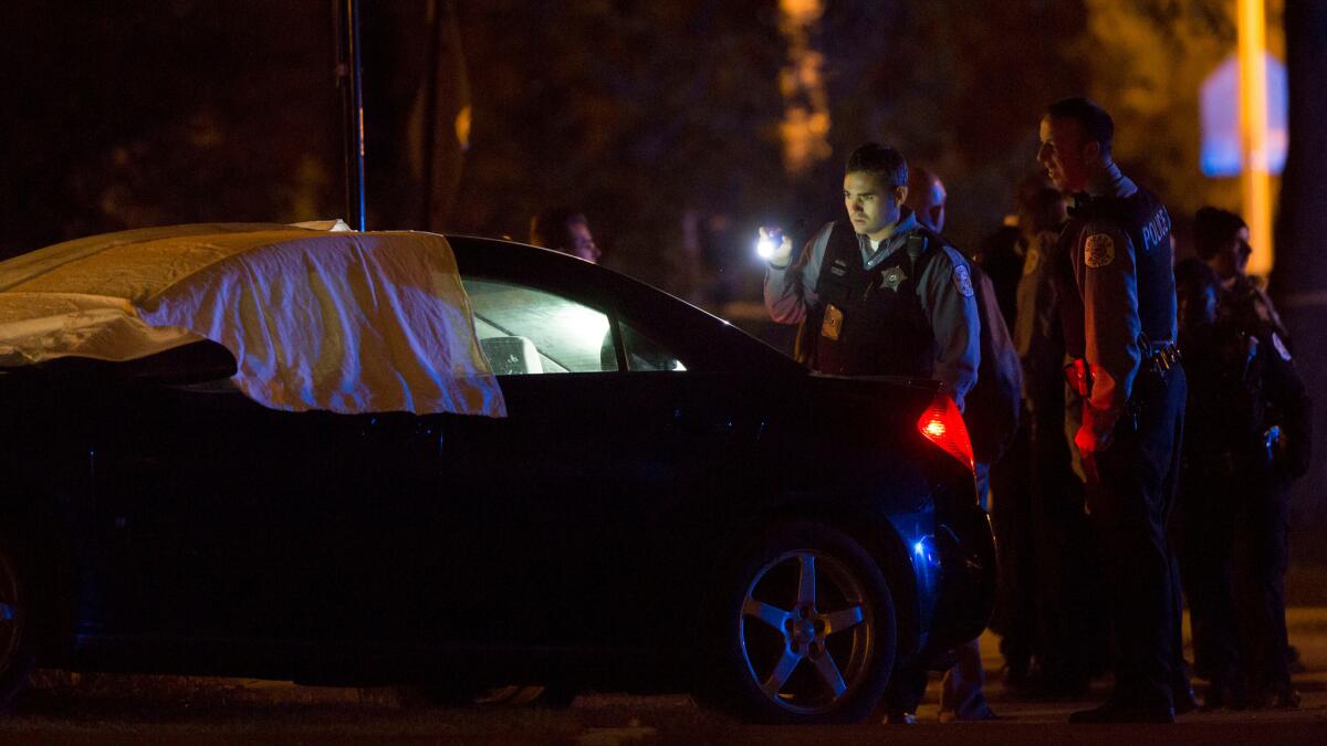 Chicago police officer looks inside a vehicle after a homicide.