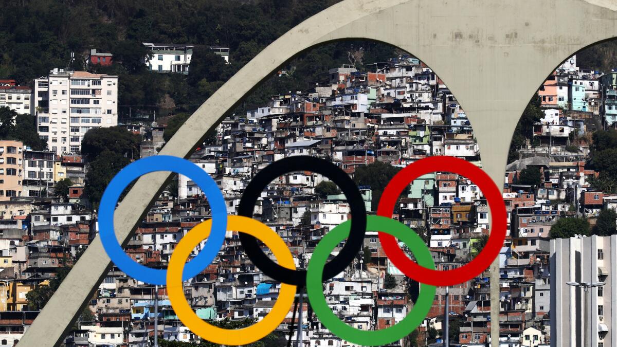 Favelas crowd a hillside as seen through the Olympic rings at the archery center in Rio de Janeiro.