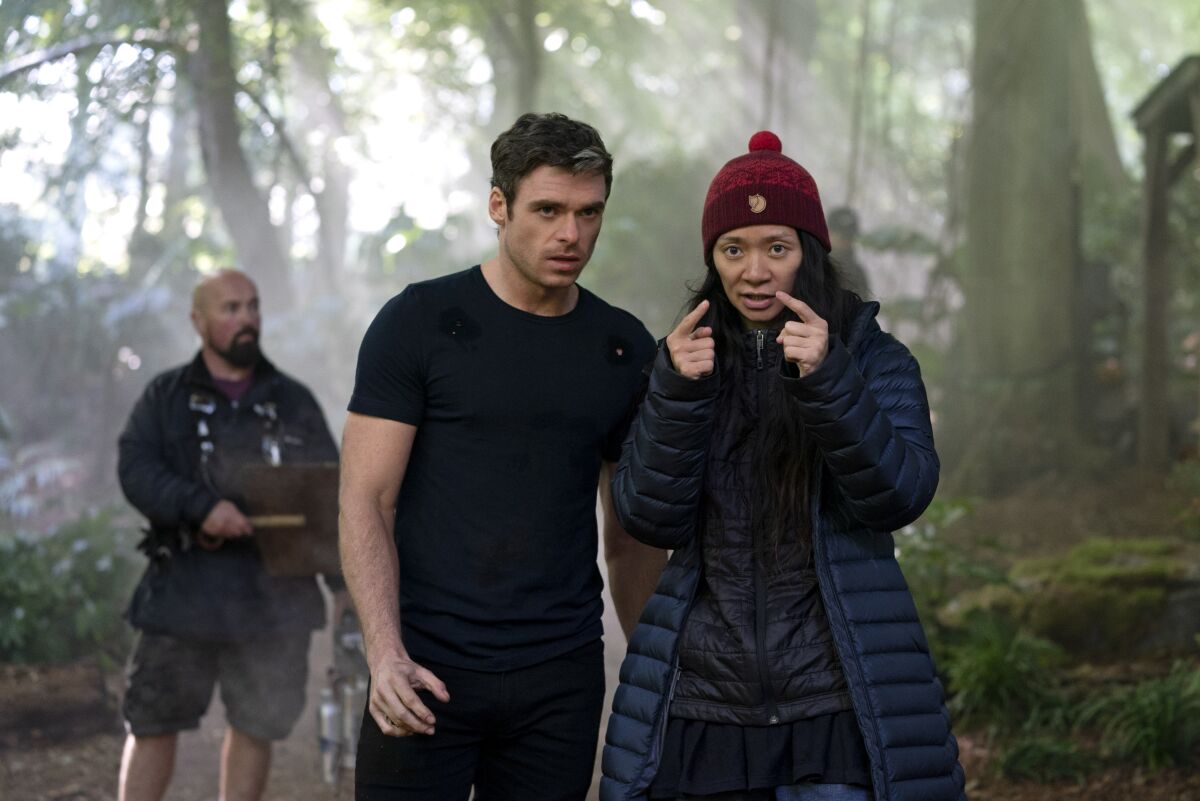 A woman, right, speaking to a man in a forest.