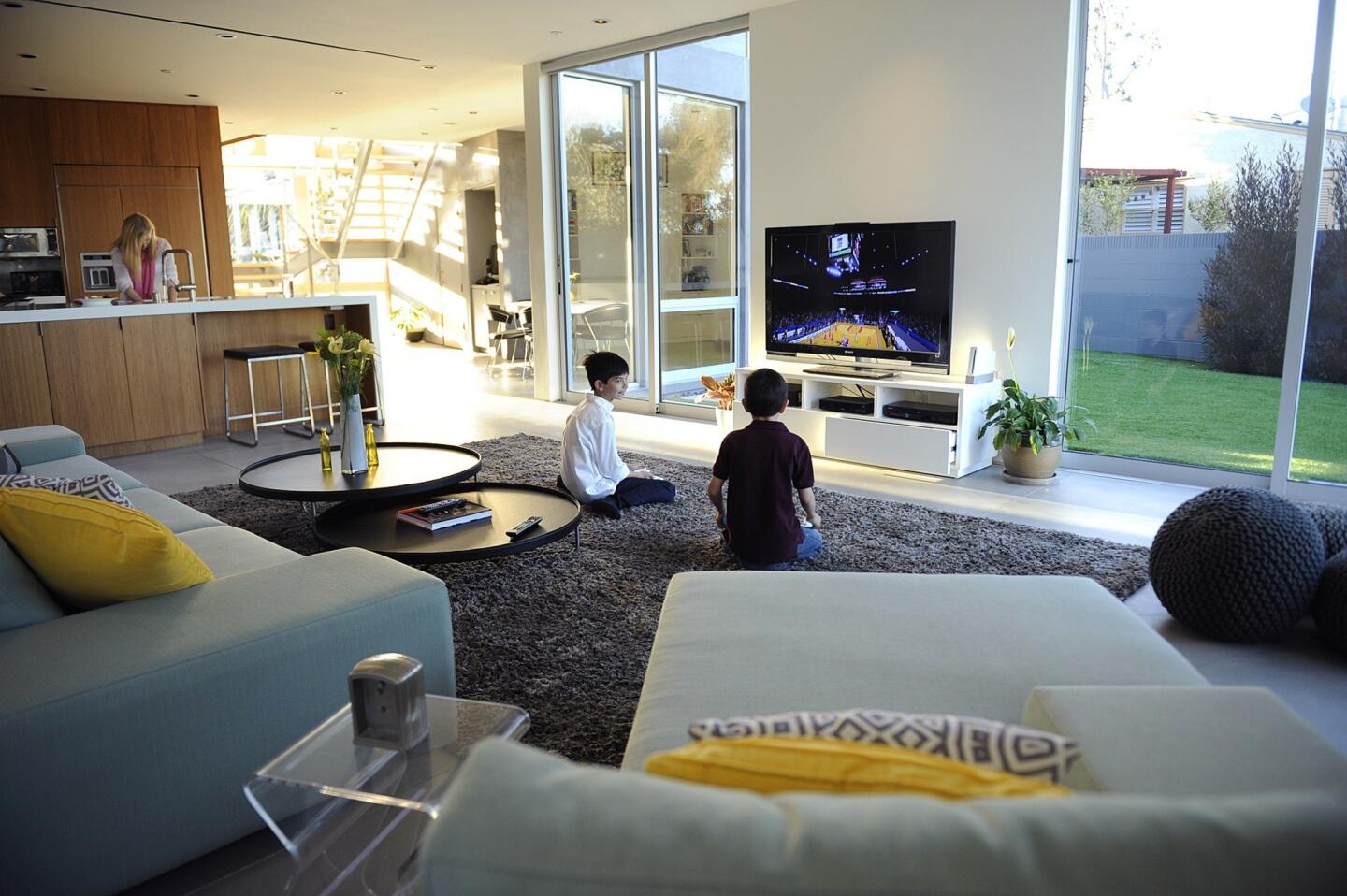 Tanner and Kyle Chen play a video game while their mom, Tiffany, makes dinner. The kitchen sink is the command and control center, with sightlines to wherever the kids are playing — family room or backyard.