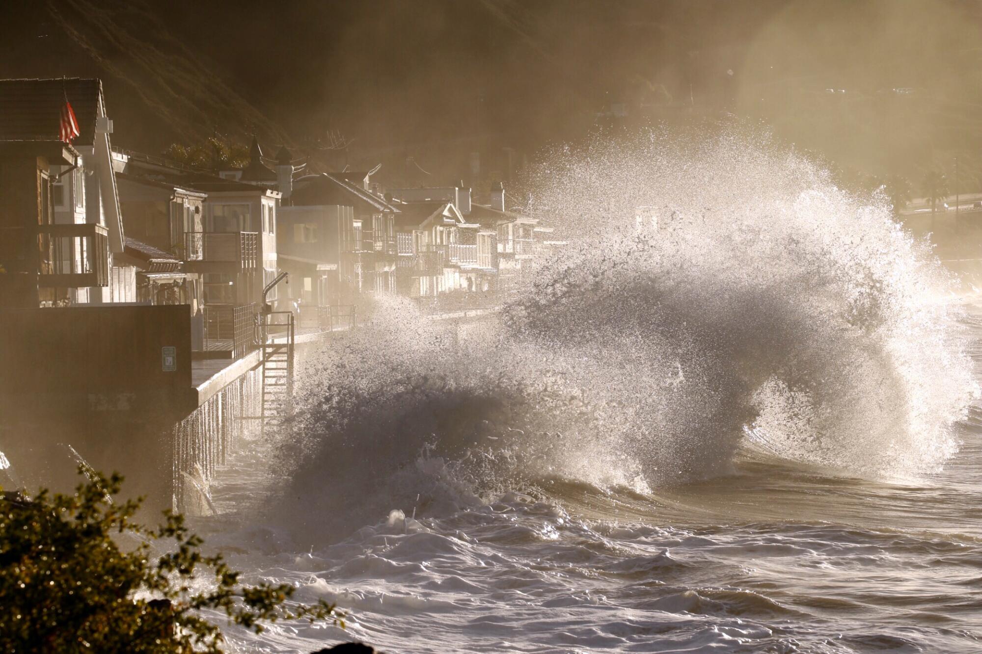 Enormous waves crash into a seawall near a residential community.