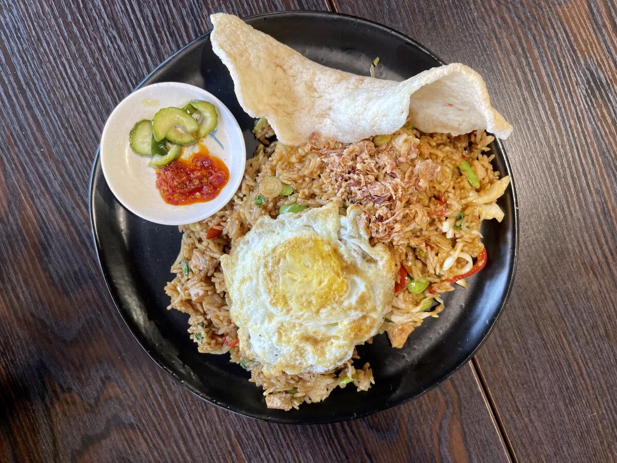 Nasi goreng pete topped with a fried egg with a large shrimp chip and garnishes