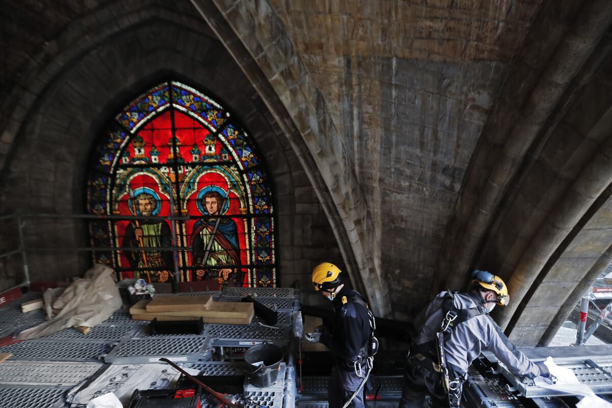 Notre Dame Katedrali'nin yeniden yapılanma alanındaki kasaların altındaki vitray pencerenin yanındaki işçiler