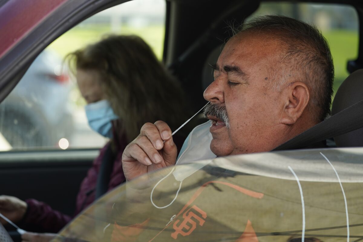 A man takes a self-administered coronavirus test in a car