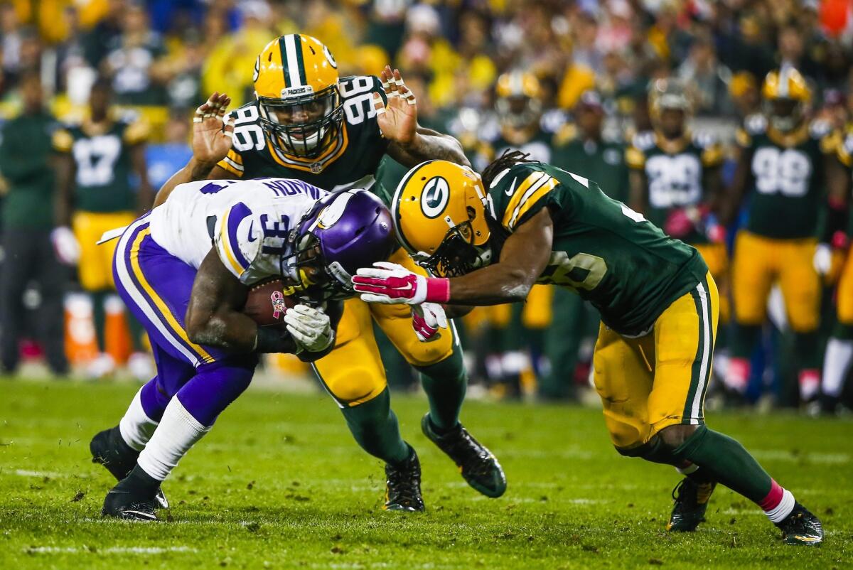 Green Bay's Tramon Williams, right, and Mike Neal look to take down Minnesota's Jerick McKinnon during the Packers' 42-10 victory Thursday night.