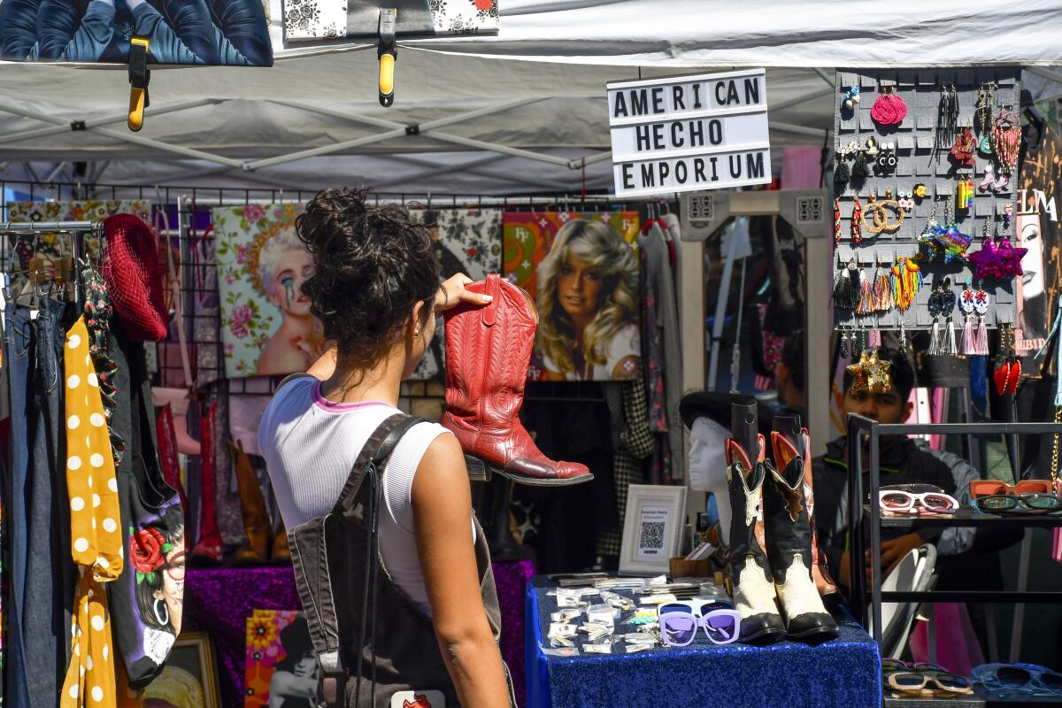 A woman inspects a cowboy boot at an outdoor flea market