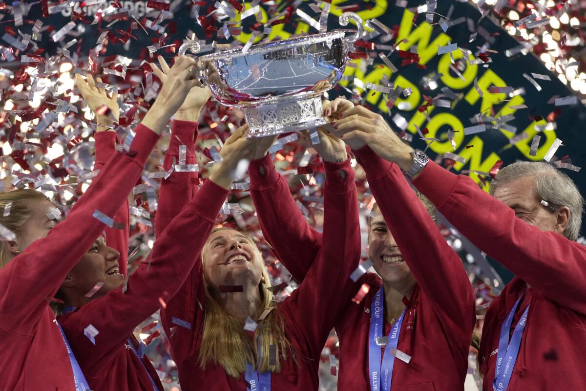 Switzerland's players Simona Waltert, Viktorija Golubic, Jil Teichmann, Belinda Bencic and Switzerland team captain Heinz Guenthardt, from left, celebrate with the trophy after defeating Australia to win the Billie Jean King Cup tennis finals, at the Emirates Arena in Glasgow, Scotland, Sunday, Nov. 13, 2022. (AP Photo/Kin Cheung)