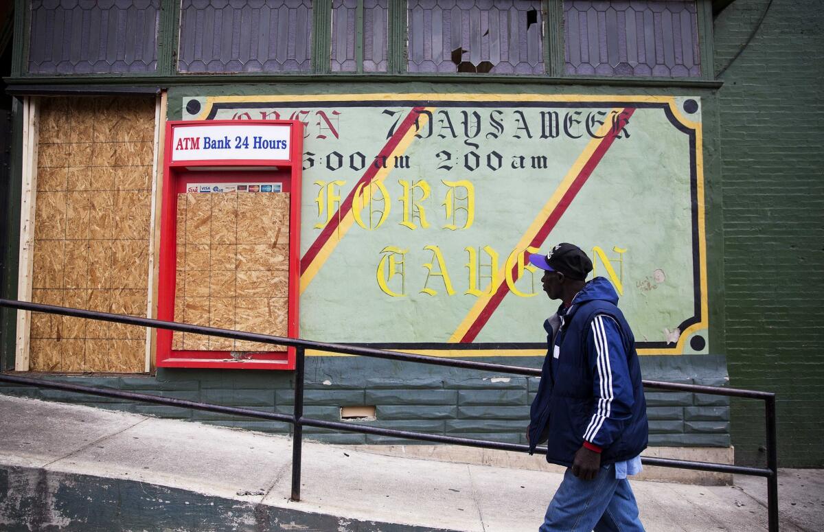 A man walks past the damaged Oxford Tavern on Thursday, April 30, 2015, in Baltimore. Richard Sung Kang’s liquor store and bar was hit by looters Monday, during a riot over the police-involved death of neighborhood resident Freddie Gray. The business wasn’t torched like the nearby CVS pharmacy, but its doors and windows were broken and cash and inventory stolen, leaving shelves bare. Now the 49-year-old South Korean immigrant must decide whether to reopen. If so, it could mean taking on more debt and paying higher insurance premiums. (AP Photo/David Goldman)