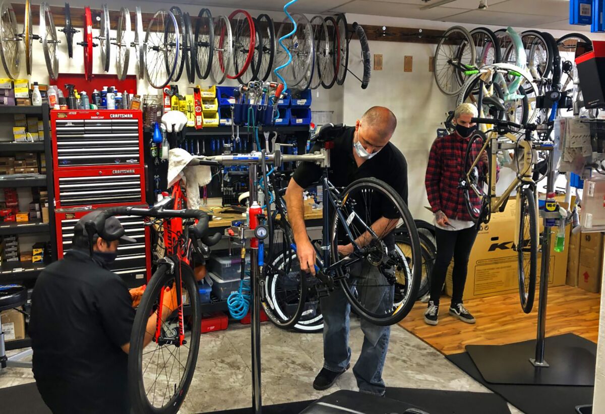 Dan Zapkoski (center), owner of Pacific Beach Bikes, works in his retail shop on Grand Avenue in Pacific Beach.
