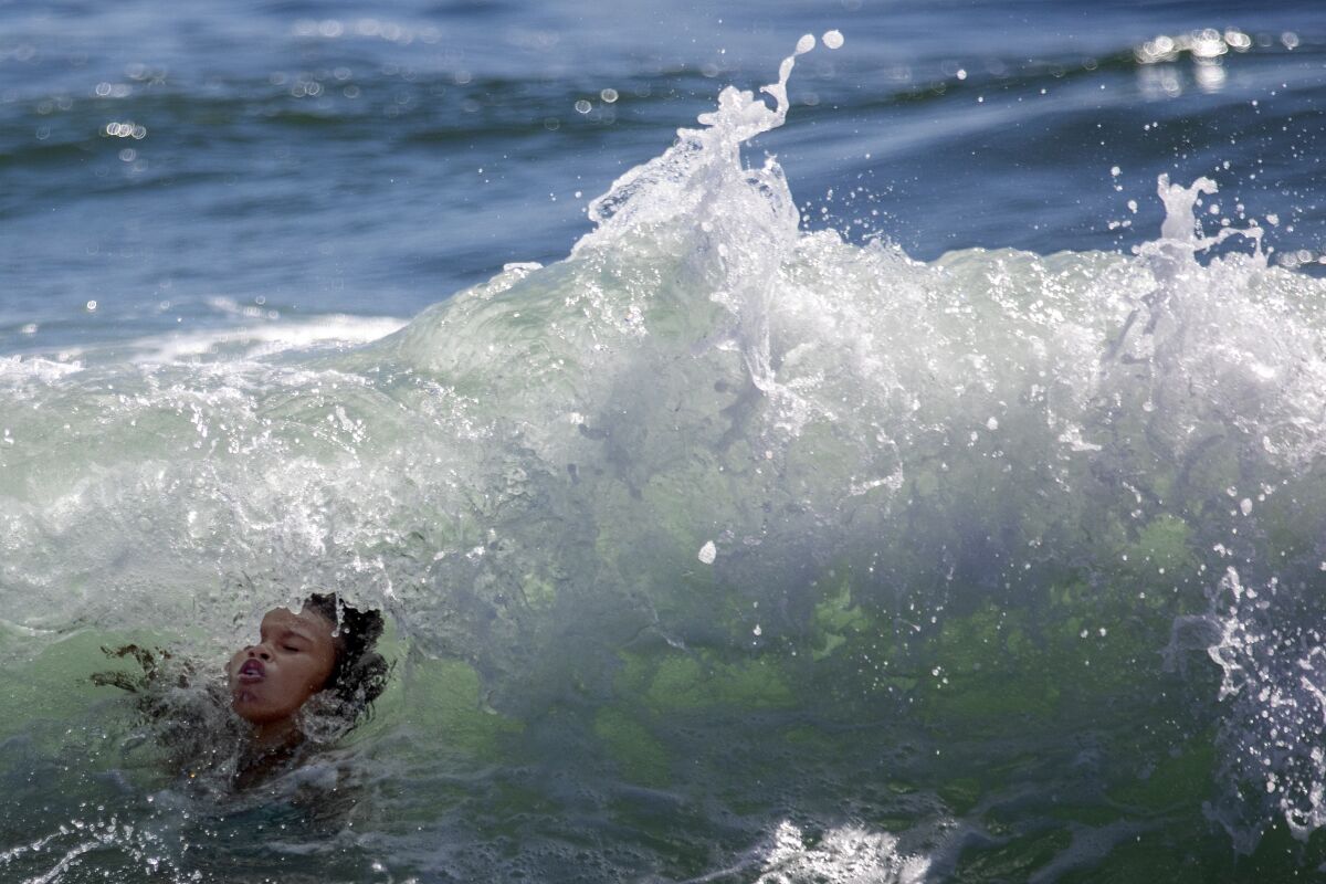 An ocean wave washes over a child